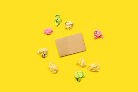 A small blank brown paper surrounded by colored paper buns on a yellow background