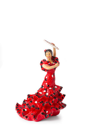 A doll dressed as a flamenco dancer holding a fan on a white backgroundの写真素材