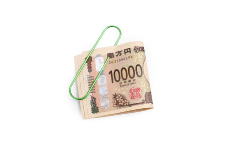 Ten thousand yen bank notes held by a green metal clip on a white background with copy spaceの写真素材