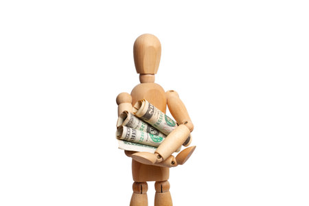A wooden mannequin holding rolled dollar bills on white background with copy spaceの写真素材