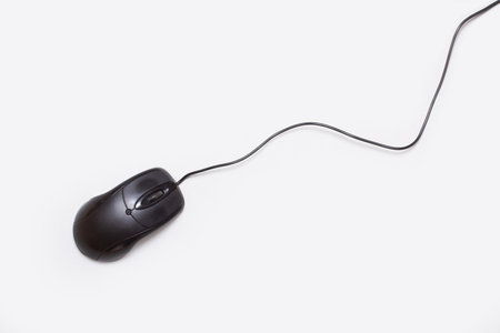 A black computer mouse with cable on a white backgroundの写真素材