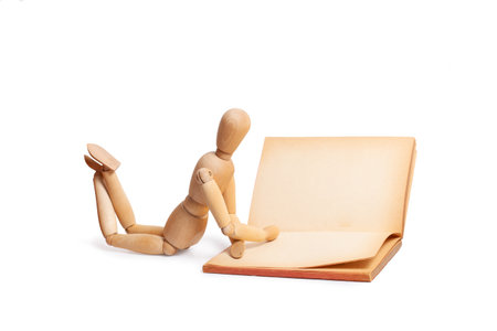 A wooden mannequin reading a book isolated on a white backgroundの写真素材
