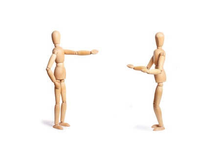 Two wooden toy mannequins doing speaking gestures isolated on a white background with copy spaceの写真素材