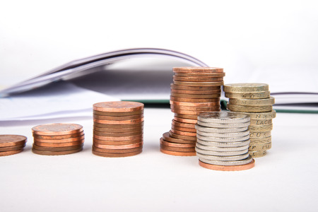 British pound sterling coins and notes with financial chart in background