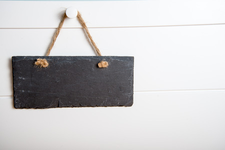 Black stone slate blank sign hanging on white wooden doorの写真素材