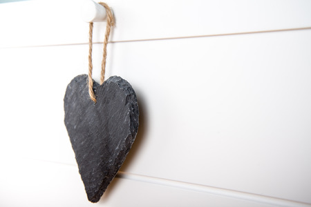 Black stone slate herath shape blank sign hanging on white wooden doorの写真素材