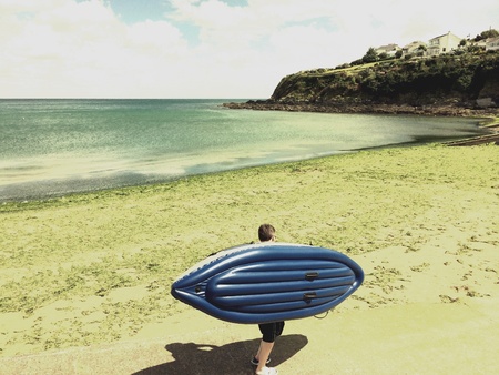 Man walking on Cornish beach with kayakの素材