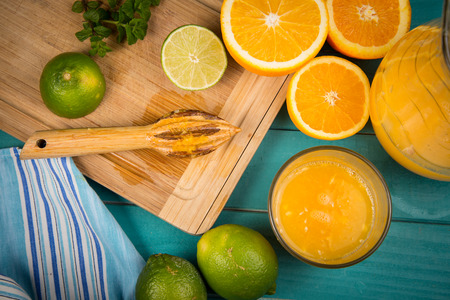 Fresh organic homemade orange and lemon juice preparation on rustic wooden kitchen table in vivid colour and blue backgroundの写真素材