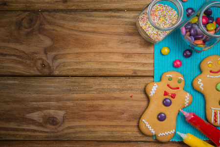 Home made gingerbread men decorating for Christmas on wooden background