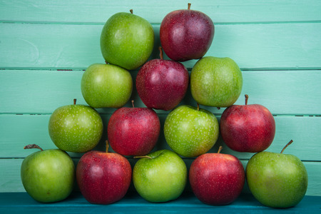 Farm fresh pyramid of organic red and green autumn apples on wooden retro pastel color table and wood backgroundの写真素材