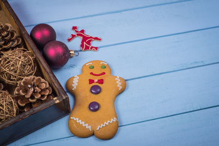 Retro box with Christmas decorations on wooden background with gingerbread manの写真素材