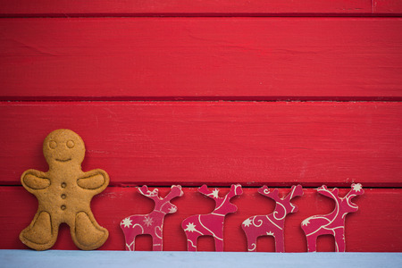 Gingerbread man and reindeer on red wooden background