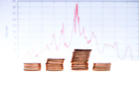 stack of coins over financial graph on white
