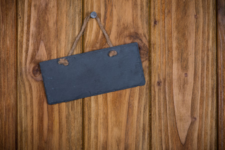 Stone signboard with rope hanging on wooden backgroundの写真素材