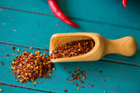 Scoop with hot chilli seeds on wood background