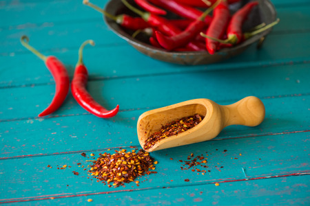 Organic red peppers and scoop with dried seeds on blue tableの写真素材