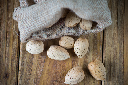 Almonds in sack on wooden rustic tableの写真素材