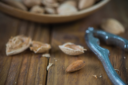 Whole almonds and nut crusher on wooden table
