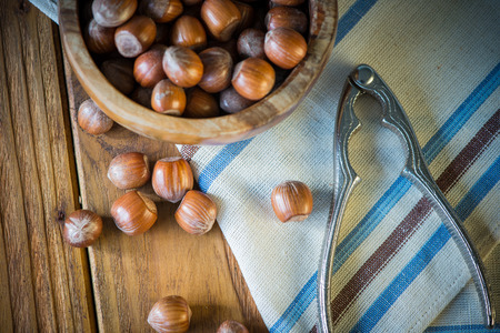 top view over hazelnuts in bowl and nut cracker on clothの写真素材
