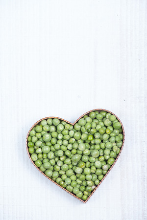 heart shape with fresh green peas on white wooden tableの写真素材
