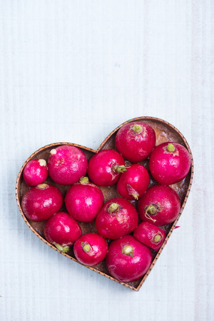 fresh radish  in heart shape on wooden tableの写真素材