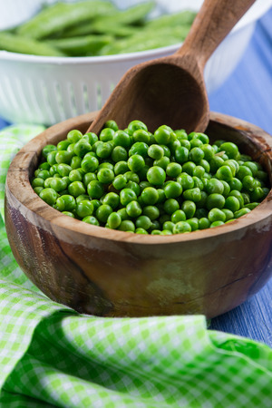 Wooden bowl with fresh sweet petite peas and scoopの写真素材