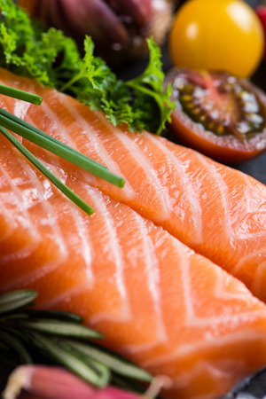 Portion of fresh salmon with spices,herbs and vegetables on black slate backgroundの写真素材