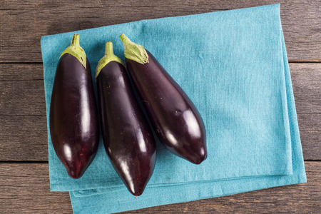 Vibrant fresh aubergine on rustic wooden tableの写真素材