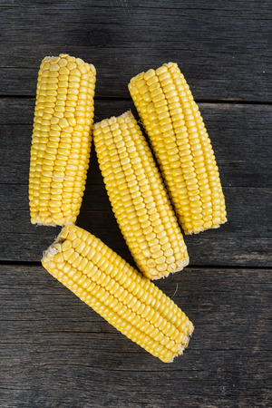 whole corn cob on rustic wooden table from aboveの写真素材