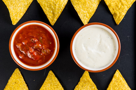 mexican street food nachos  with salsa and cream dip on black background
