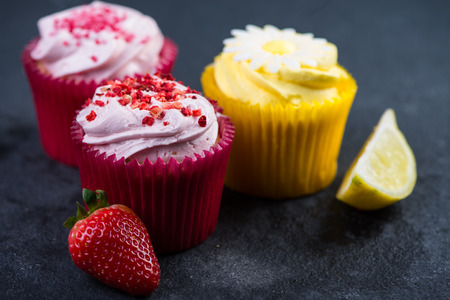 Strawberry and lemon cupcakes with fresh fruit on dark backgroundの写真素材