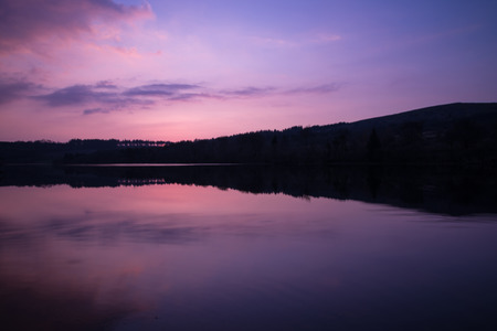 colorful and relaxing sunset over calm lake with reflection in waterの写真素材