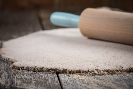 rolling wholegrain dough for homemade bread on wooden rustic tableの写真素材