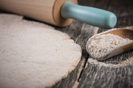 rolling wholegrain dough for homemade bread on wooden rustic tableの写真素材