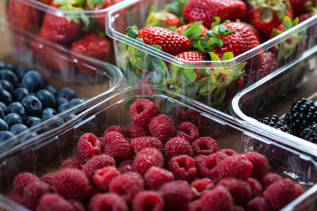 Farm fresh berries fruit in plastic trays on wodden tableの写真素材