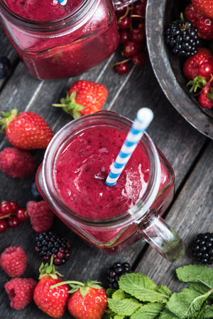 Summer berries smoothie in mason jar on rustic wooden tableの写真素材