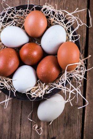 Farm fresh free range eggs in rustic bowl, on wooden tableの写真素材