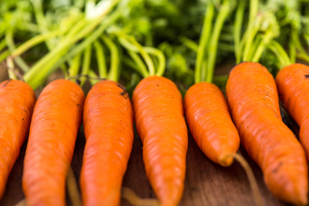 food background, farm fresh vibrant carrots on wooden tableの写真素材