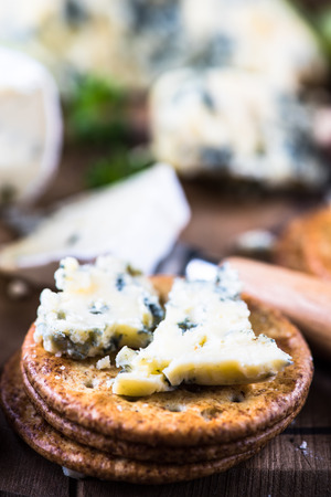 Oat crackers with cheese selection on wooden rustic boardの写真素材