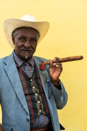 Havana, Cuba - September 27, 2015: Traditional Cuban man posing for photos while smoking big cuban cigar on yellow wall background in Havana, Cuba.のeditorial素材