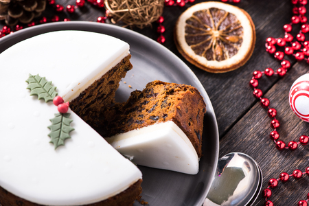 Christmas fruit cake on wooden table with festive decorationsの写真素材
