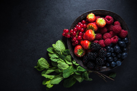 Fresh berries in rustic bowl, antioxidant concept, food border backgroundの写真素材