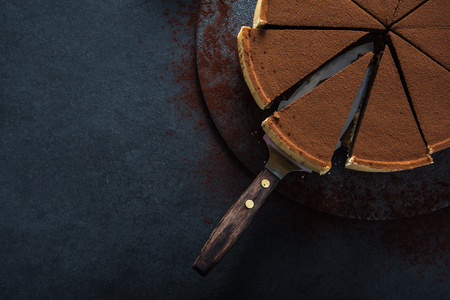 Sliced chocolate tort on dark background, overhead view