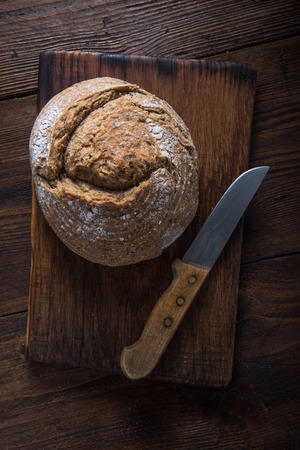 Homemade bread loaf with vintage knife on wooden cutting boardの写真素材