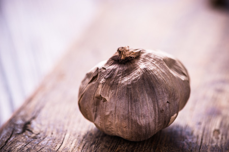 Whole balsamic black garlic on wooden boardの写真素材