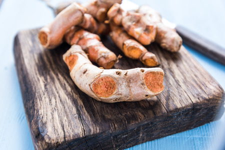 Garden fresh tumeric spice root on wooden board, from overhead