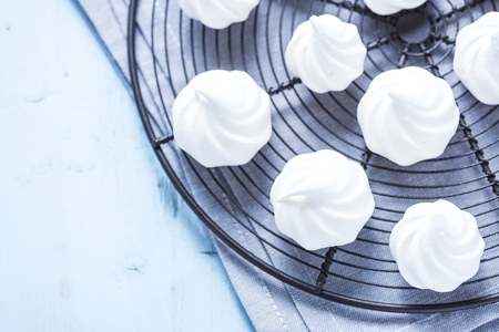 Home baked meringue on cooling tray, view from overhead. Bright colors and blue pastel background.の写真素材