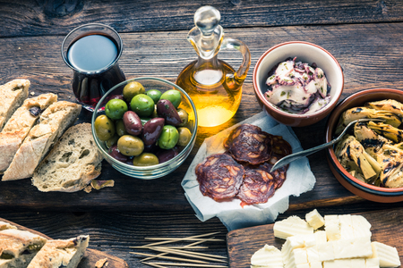 Tapas served in restaurant or bar on wooden table, with red wine meat and bread.の写真素材