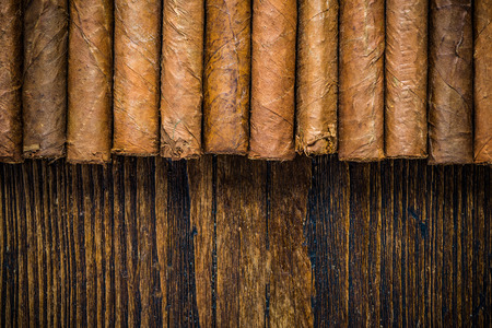 Hand rolled cigars on wooden table, border background, flat view from above. Space for text or advert.の写真素材