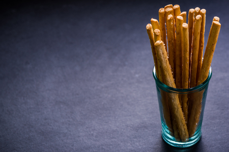 Bread sticks with salt in glass jar, on dark border background